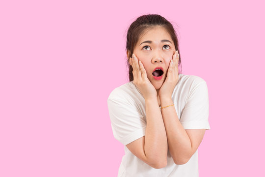 Cute Asian Woman Gets Shocked And Surprised, Hands Around Her Mouth, Unhappy Feeling, White Shirt, Pink Background