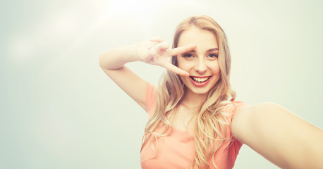 smiling woman taking selfie and showing peace sign