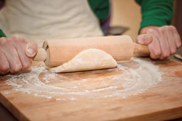 Hands with rolling pin and cookie dough.Selective focus.