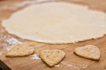 Heart shaped cookies and dough on a wooden board.Selective focus.
