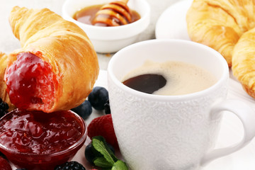 Delicious breakfast with fresh croissants and ripe berries and jam