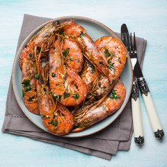 Grilled shrimps with parsley on pastel turqouise background. Shellfish dish