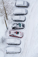 Cars covered in snow on a parking. Top view.