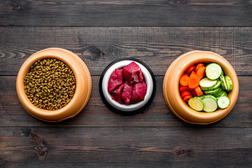 Ingredients for dry pet food. Meat and vegetables zucchini and carrot on dark wooden backgroud top view copy space