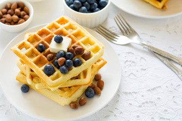 Healthy breakfast. Belgian waffles with butter, blueberry and nuts on white tablecloth. Selective focus