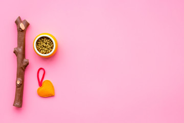 Pet care concept. Toys near bowls with animal feed on pink background top view copy space