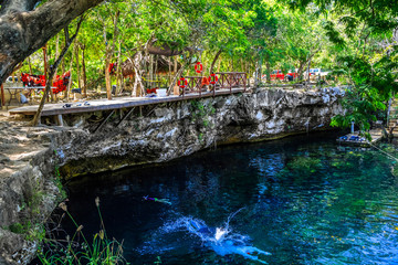 Человек прыгает в голубое озеро. Сенот Мексика