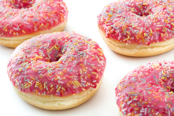 Pink frosted donut with colorful sprinkles. Isolated on white background 
