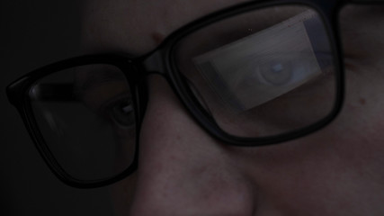 Man, face, with glasses, reflection, looking at graphics and work on the Internet, black background.