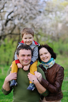 Young family - mom, dad and little son playing in the park against the background of spring green trees