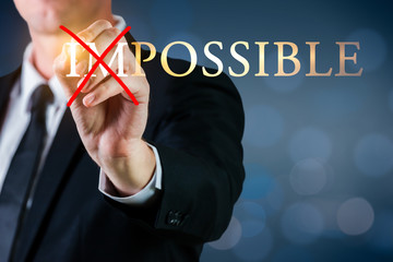 Man holding a pen to cross impossible possible word