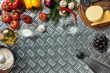 Food ingredients and spices for cooking pizza. Mushrooms, tomatoes, cheese, onion, oil, pepper, salt, egg, grater on metal background. Copy space. Top view