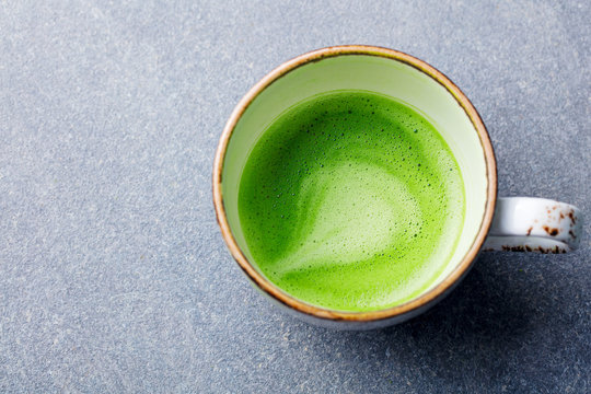 Matcha, green tea latte in a cup. Grey stone background. Top view. Close up.