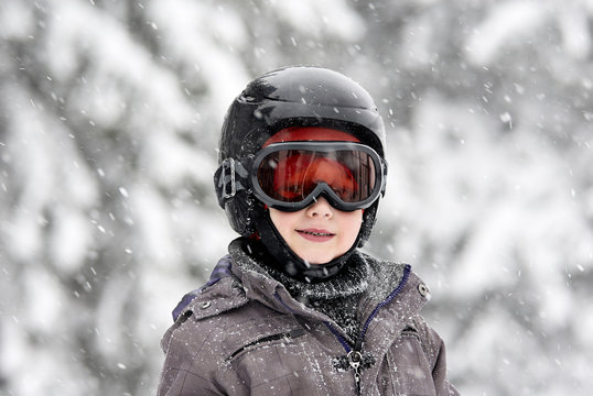 Child boy skiing in mountains. Active teenager kid with safety helmet and goggles. Ski race for young children. Winter sport for family. Young skier racing in snow
