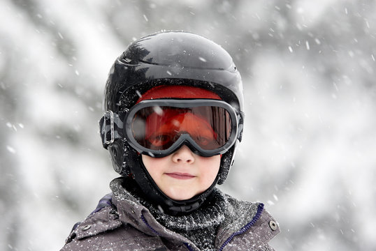 Child boy skiing in mountains. Active teenager kid with safety helmet and goggles. Ski race for young children. Winter sport for family. Young skier racing in snow

