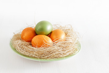 Happy Easter concept. Easter eggs in nest on white wooden table. Angle view.