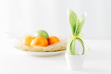 Easter bunny gift egg against Easter eggs in nest on blurred background