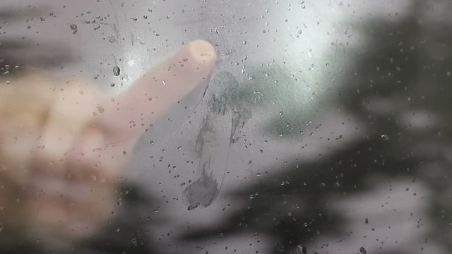 Finger drawing two hears on a car window covered with steam