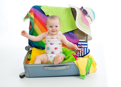 Baby girl sitting in trunk with things for vacation travel