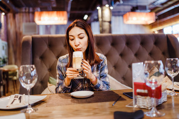 Beautiful young brunette eastern woman sitting in cafe and drinking latte coffee