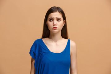 The awkward woman standing and looking at camera against pastel background.