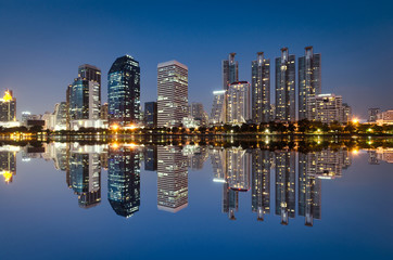 Fototapeta na wymiar light from modern building bright in night city with skyline symmetric water mirror reflection. night cityscape concept.