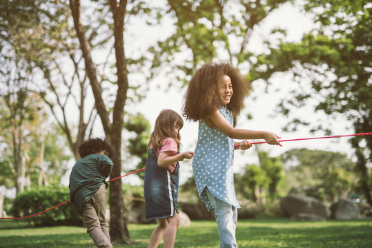Happy children playing tug of war at the park