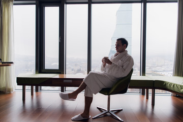 man in bathrobe drinks coffee in luxury hotel in the morning looking at camera