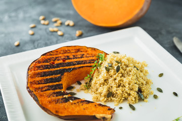 Delicious baked pumpkin with sprouted millet and pumpkin grains on the dark table