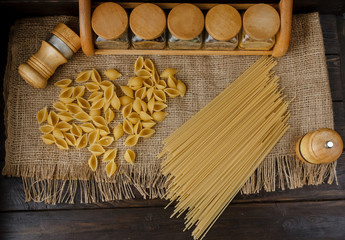 Raw pile of macaroni scattered on the linen table cloth. Healthy lifestyle and eating habits....