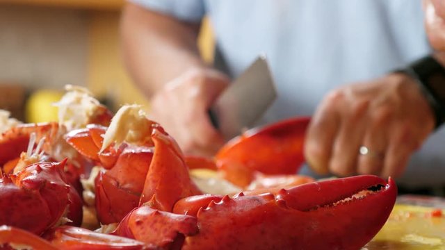 Hands chop fresh boiled hot red lobster for dinner