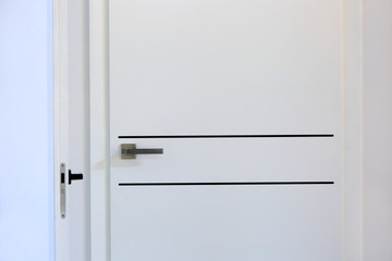 Białe drzwi wejściowe do mieszkania, zbliżenie, klamka.