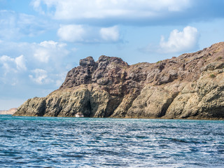 Fototapeta na wymiar the rocky shore. high rocky cliff and boat at sea
