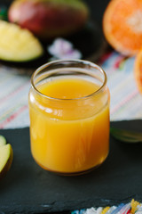 Fresh mango and orange detox drink over black slate.