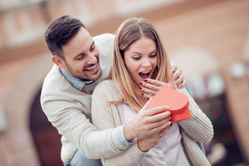 Smiling boy giving to his girlfriend a gift.