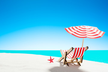 A chaise longue under an umbrella on the sandy beach by the sea and sky with copy space