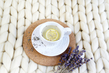 Cup with lavender tea, citrus and honey, croissant, white pastel giant knit blanket, bedroom, flowers tulips, spring, woman day, morning concept