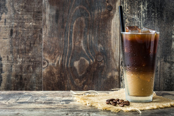 Iced coffee in glass on wooden table. Copyspace
