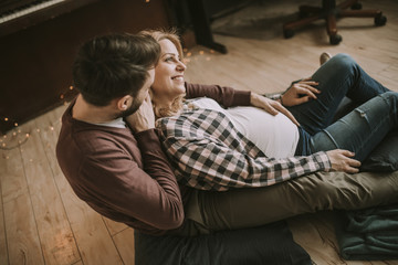 Pregnant woman with a husband sitting on the floor