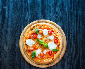 Top view of italian classic pizza margherita over a wooden table with toppings