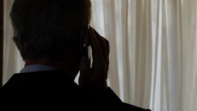 unrecognizable businessman commits financial crimes in the dark- phone tapping