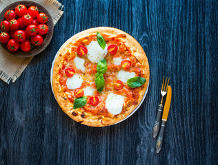 Top view of italian classic pizza margherita over a wooden table with toppings