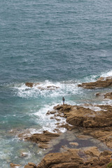 Fototapeta na wymiar Lonely angler tries to catch a fish. Brittany coast. France