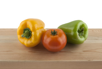 Bulgarian pepper and tomato on a wooden table isolated on white background