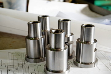Steel bushings after turning, turning, drilling, cutting. The details lie on the background of the drawings.