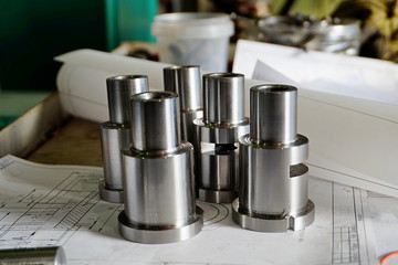 Steel bushings after turning, turning, drilling, cutting. The details lie on the background of the drawings.