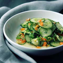 Chinese cucumber salad on the white plate. Asian cuisine. Bell pepper, cucumber and sesame seeds. Vegetarian dish. Toned photo.