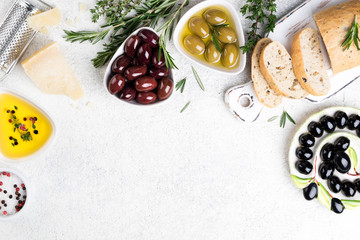 Fototapeta na wymiar Mediterranean snacks. Ciabatta bread, olives, cheese, oil, herbs and spices on white background. Copy space, top view