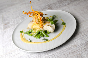 White fish baked with beans on a white plate