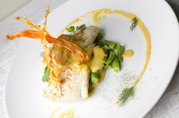 White fish baked with beans on a white plate